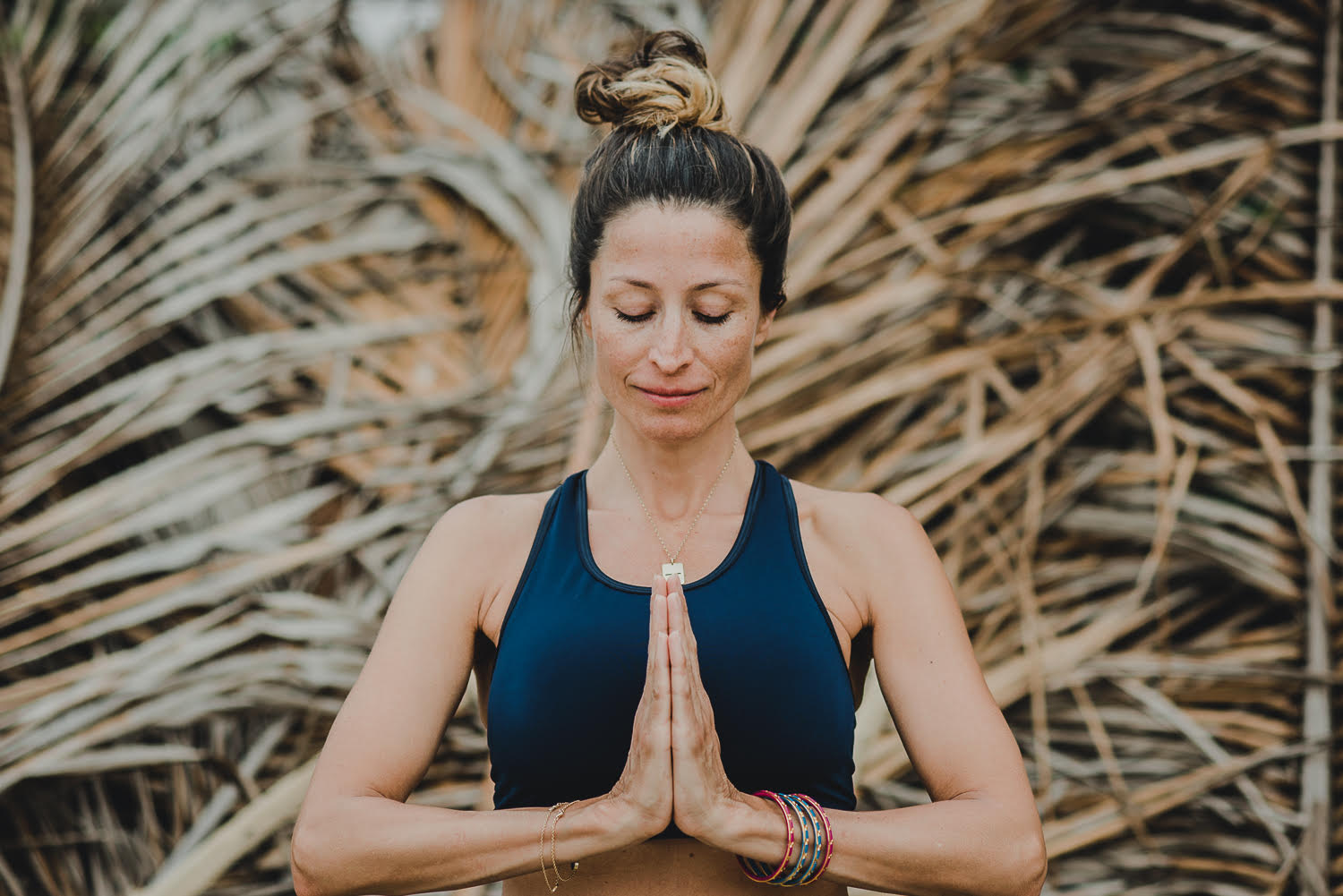 Rebecca Loos with hands together and head bowed during yoga practice.