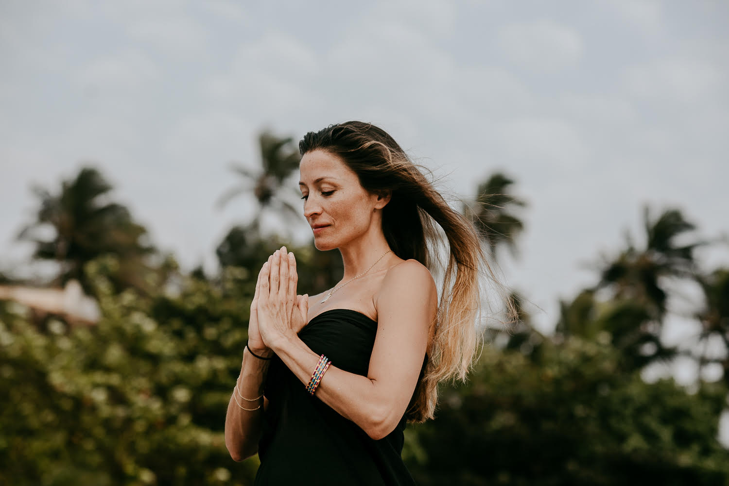 Rebecca Loos with hands together and head bowed during yoga practice.